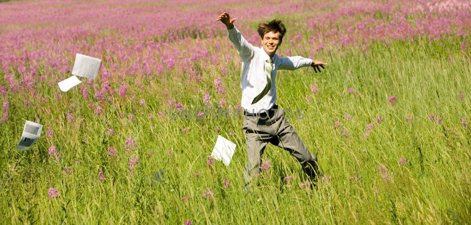 Photo of happy businessman running upon green field on windy day in summer