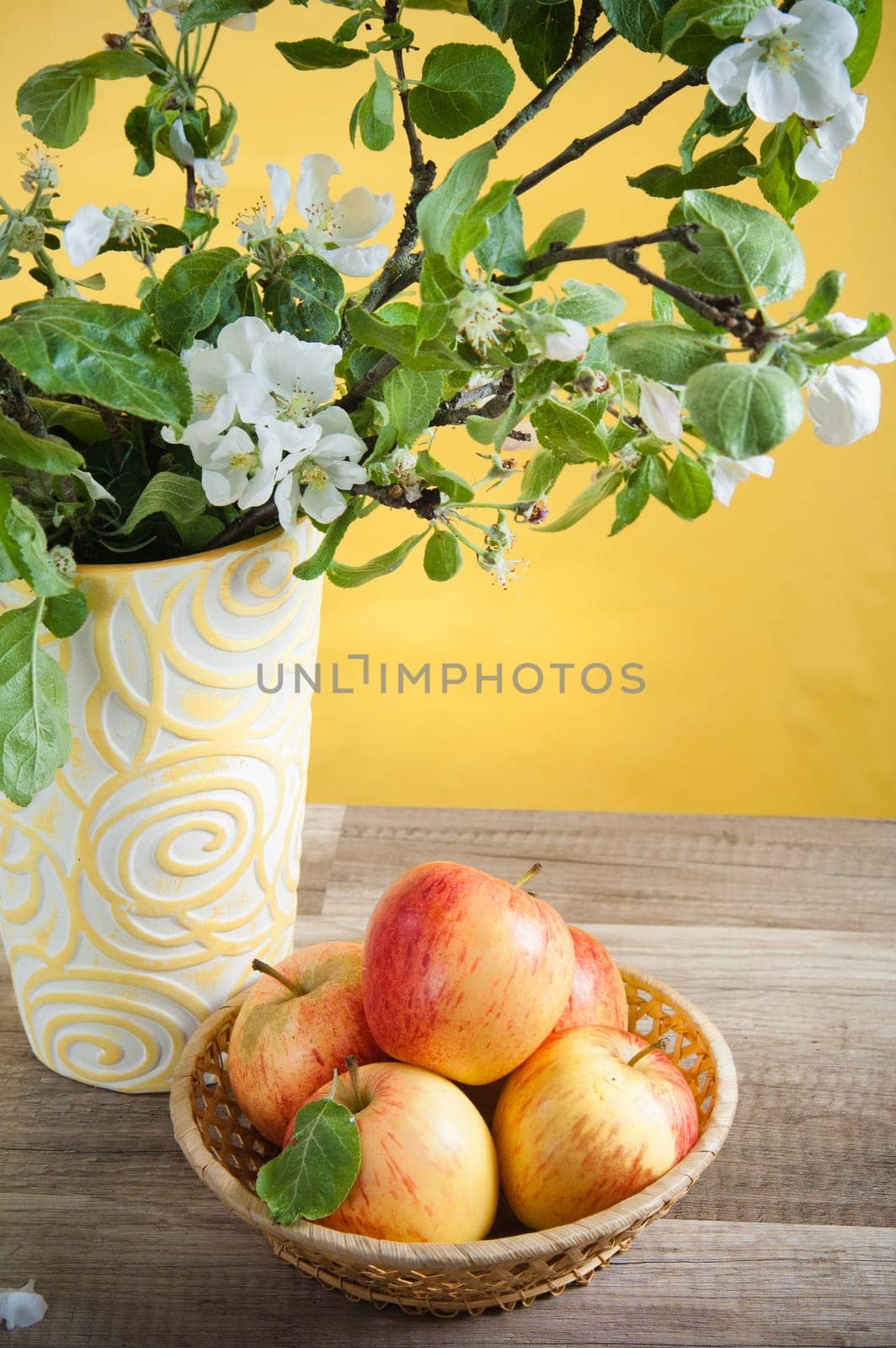 Beautiful ripe apples and branches of a blossoming apple-tree in a vase