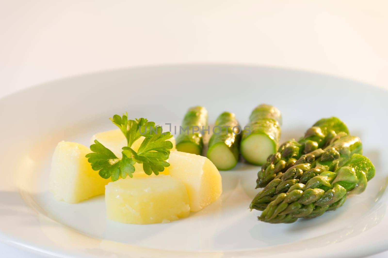 Green asparagus with potato on a white plate