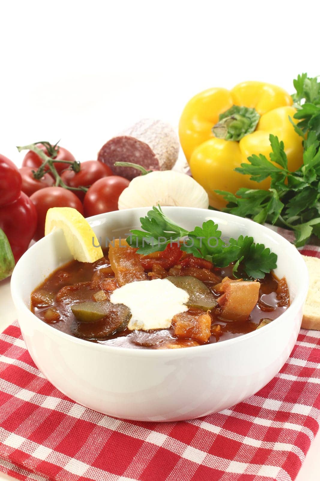 a bowl of solyanka with cream and lemon