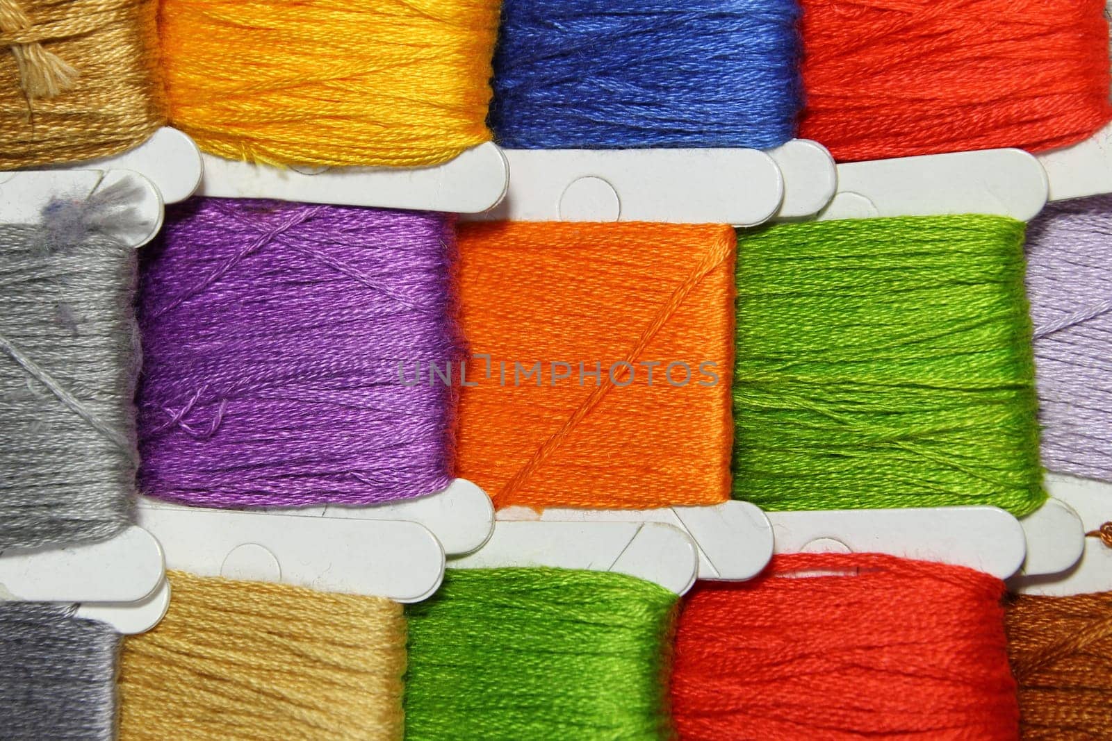 Small reels of coloured threads of red, green, blue and orange.