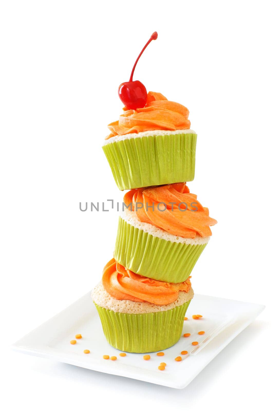Stacked vanilla cupcakes with orange colored vanilla frosting