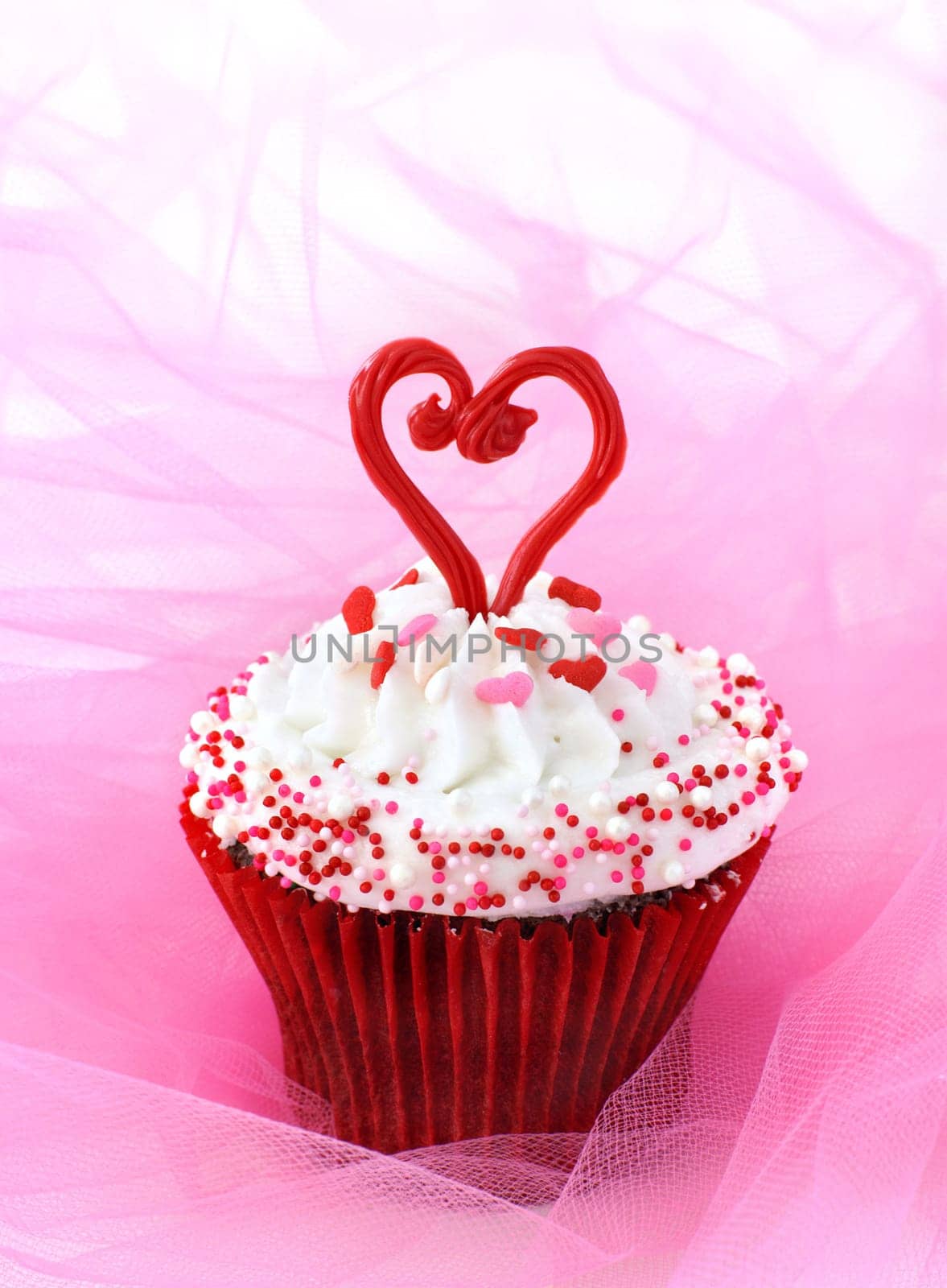 Cupcake decorated with sprinkles and a red chocolate heart