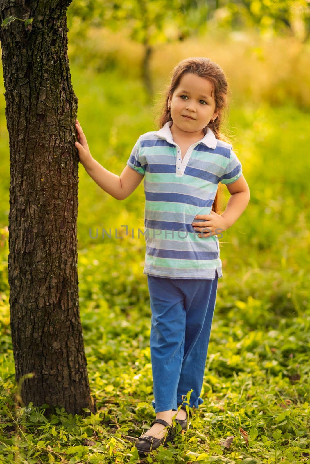 A child stands near a tree in the garden