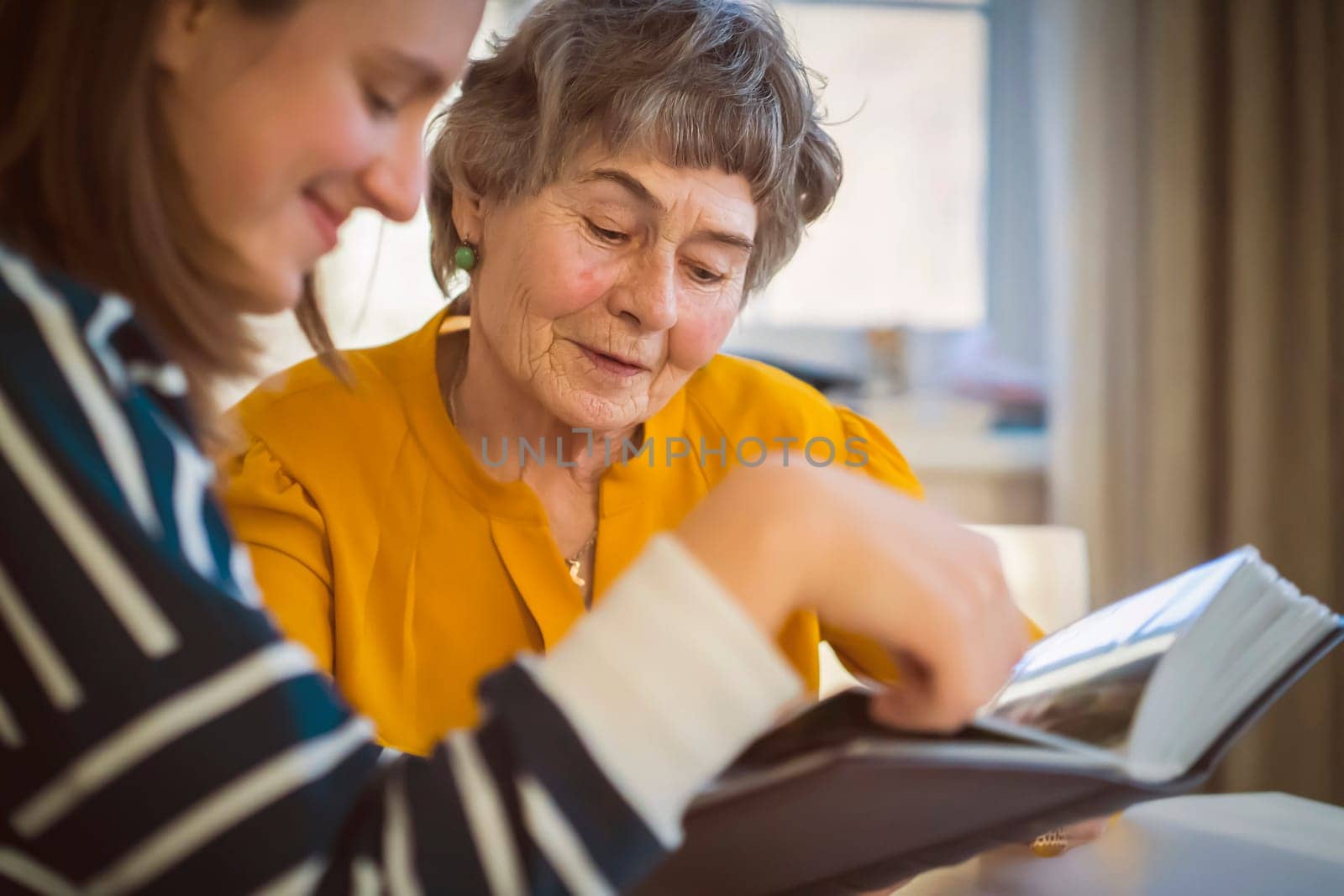 Grandmother and her young granddaughter spent great time together, family members look at photos from the youth of an elderly parent, through the pages of the album and recall funny stories from life.