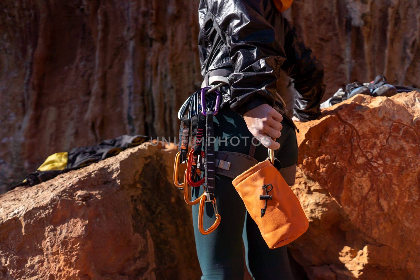A young girl is engaged in active sports, rock climbing and mountaineering. A woman looks at a beautiful red rock and takes magnesia in her hand, getting ready for training and climbing.