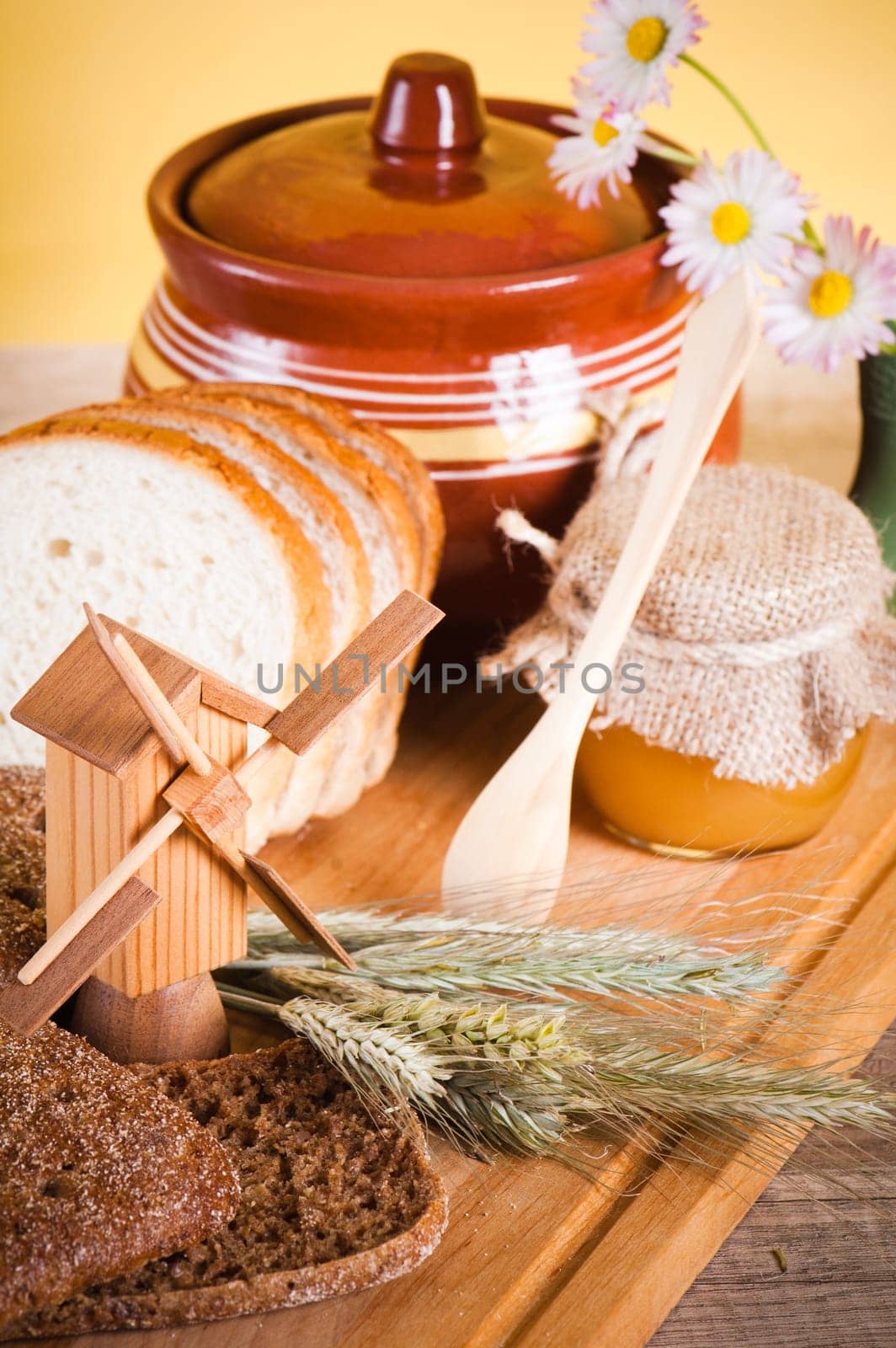 honey, flowers, spike and bread on table
