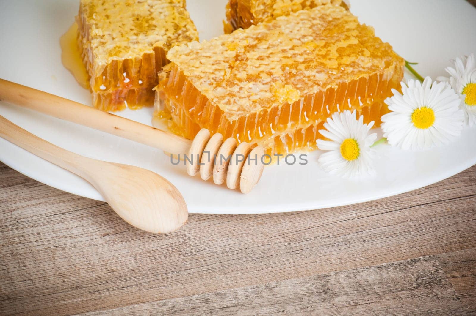 honeycomb with daisies on white plate