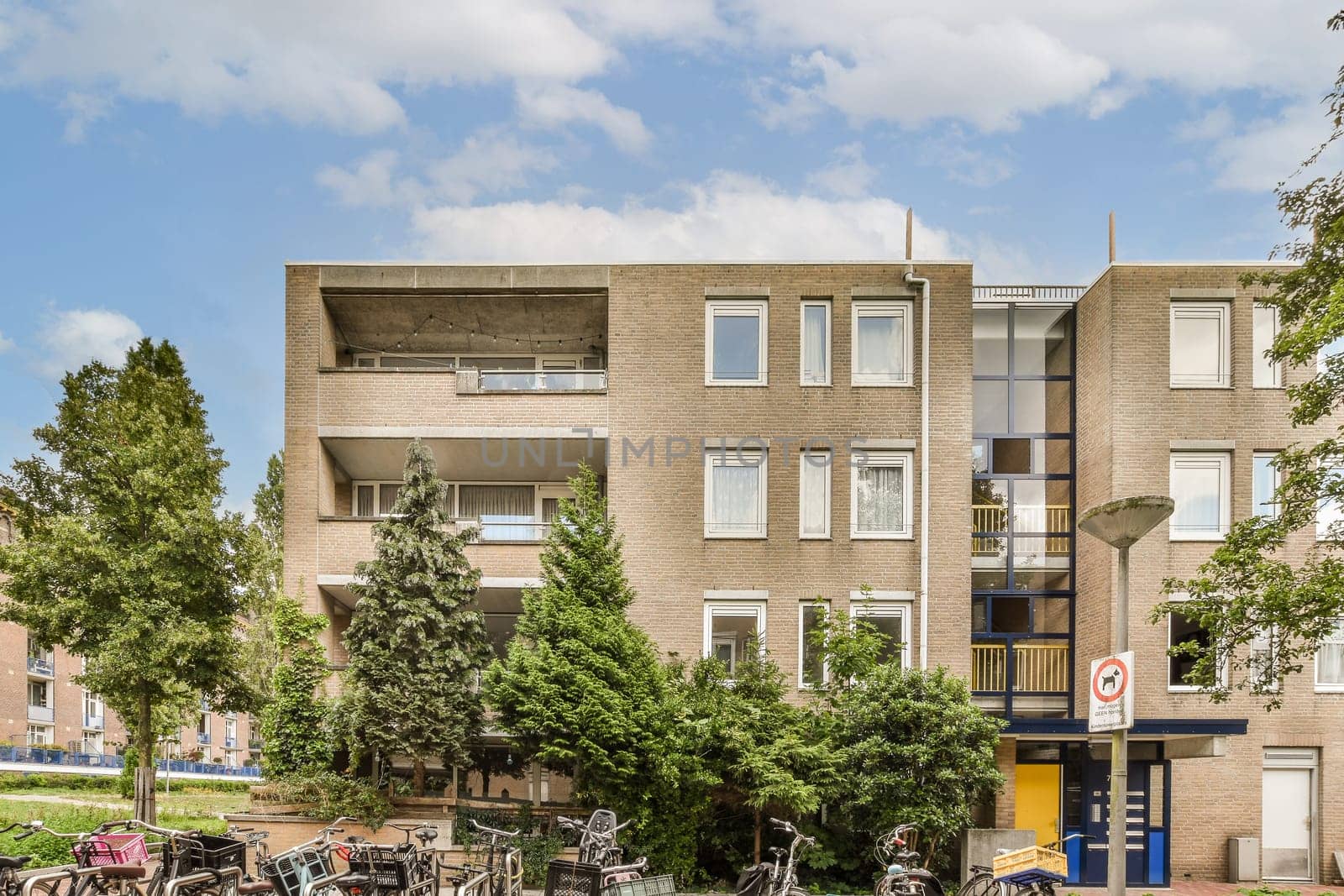 some bikes parked in front of an apartment building on a sunny day with blue sky and white fluffy clouds above