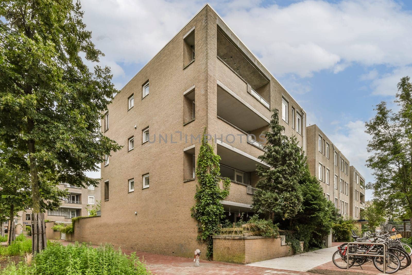 an apartment building with bicycles parked on the sidewalk in front of it and trees lining the side of the street