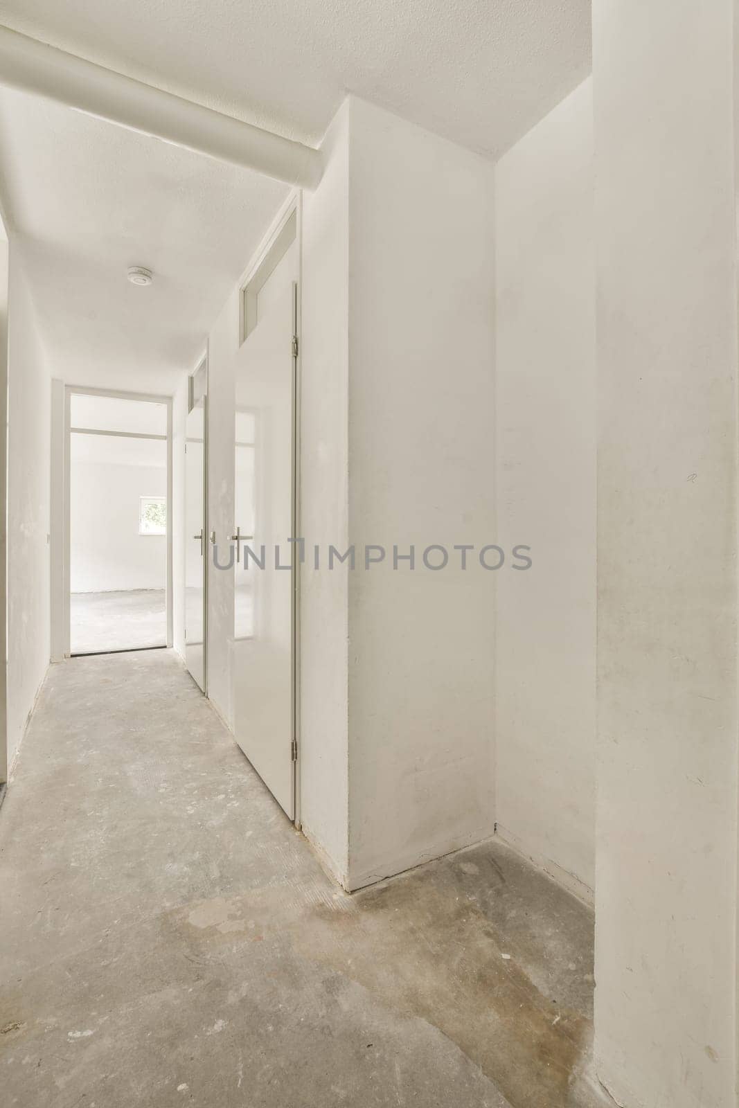an empty room with white walls and doors and cement by casamedia