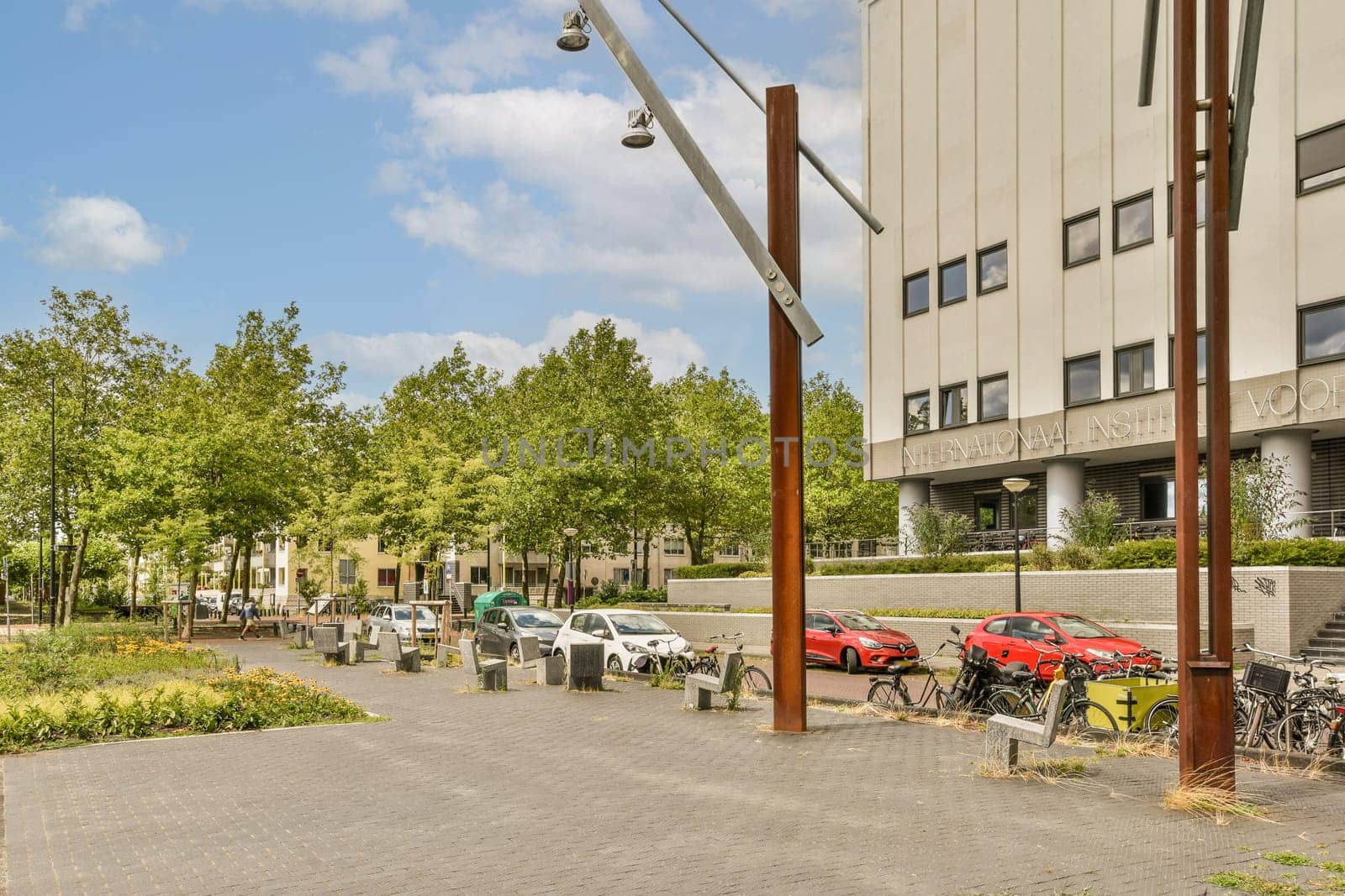 a city street with cars parked on the side and trees lining the sidewalk in front of the building behind it