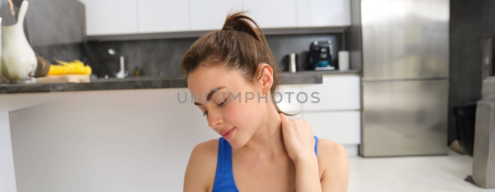 Image of woman workout at home, stretching her head and neck, does warm-up exercises before yoga, fitness training in living room.