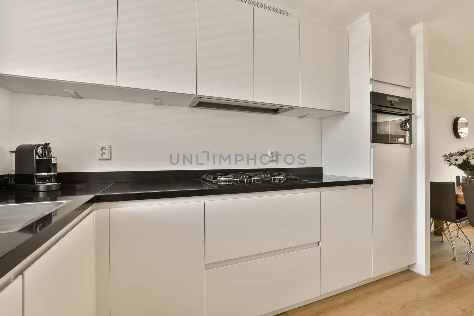 a kitchen with white cabinets and a black counter top by casamedia