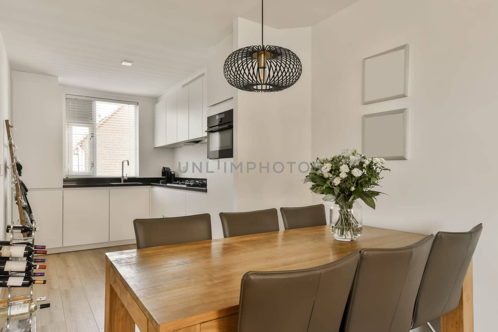 a dining room with wooden table and chairs in the middle of the room, there is a vase of flowers on the table