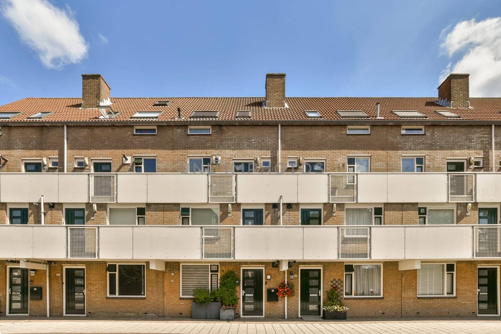 an apartment building with many windows and bales on the top floor, in front of it is a blue sky filled with white