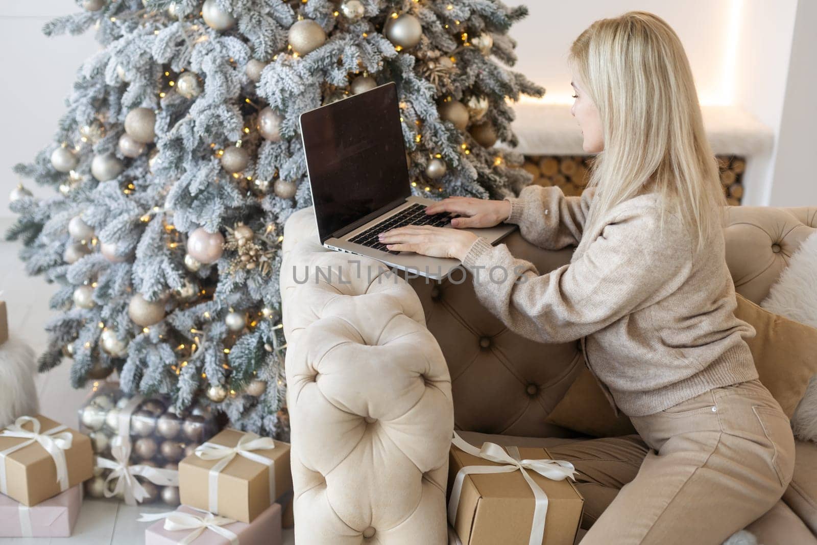 Happy young woman working on laptop in front of christmas tree. by Andelov13