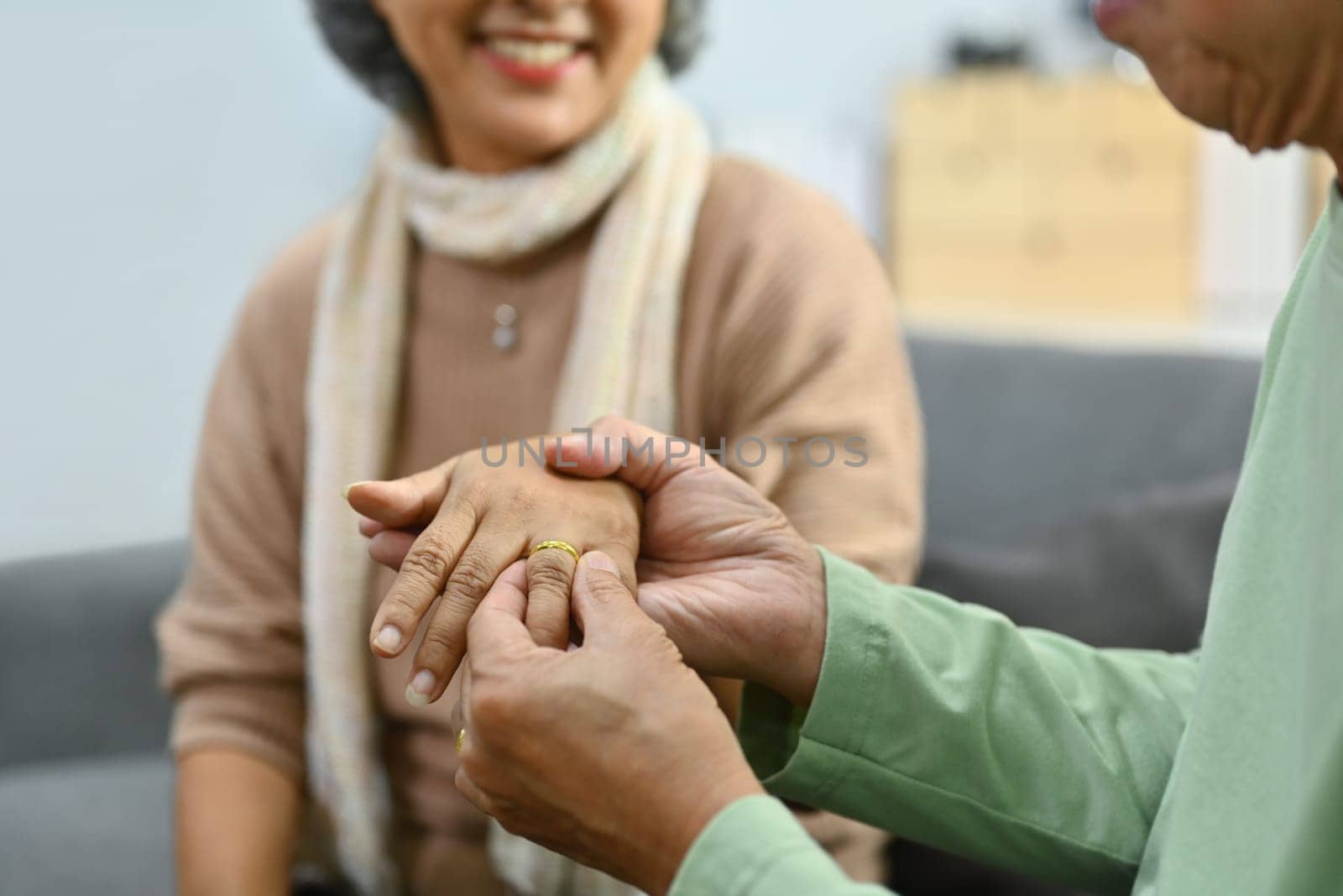 Loving senior man putting engagement ring on woman finger making marriage proposal symbol of love by prathanchorruangsak