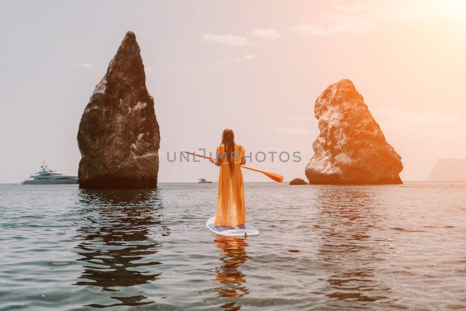 Close up shot of beautiful young caucasian woman with black hair and freckles looking at camera and smiling. Cute woman portrait in a pink bikini posing on a volcanic rock high above the sea