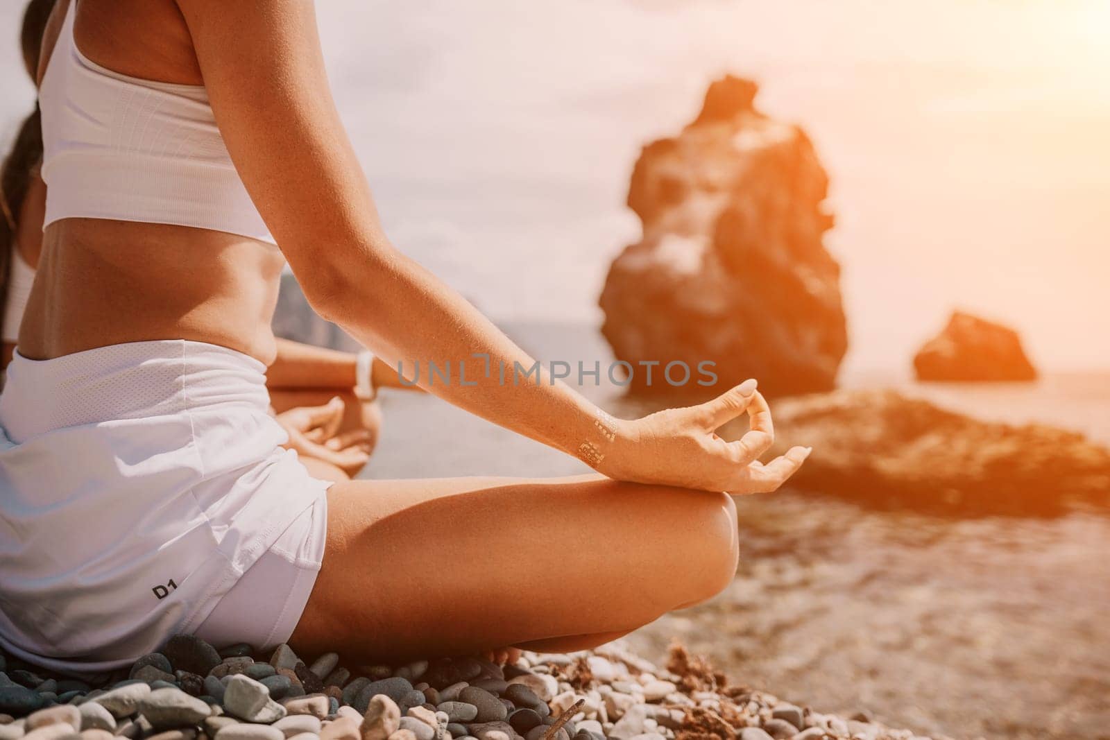 Woman sea yoga. Happy women meditating in yoga pose on the beach, ocean and rock mountains. Motivation and inspirational fit and exercising. Healthy lifestyle outdoors in nature, fitness concept. by panophotograph