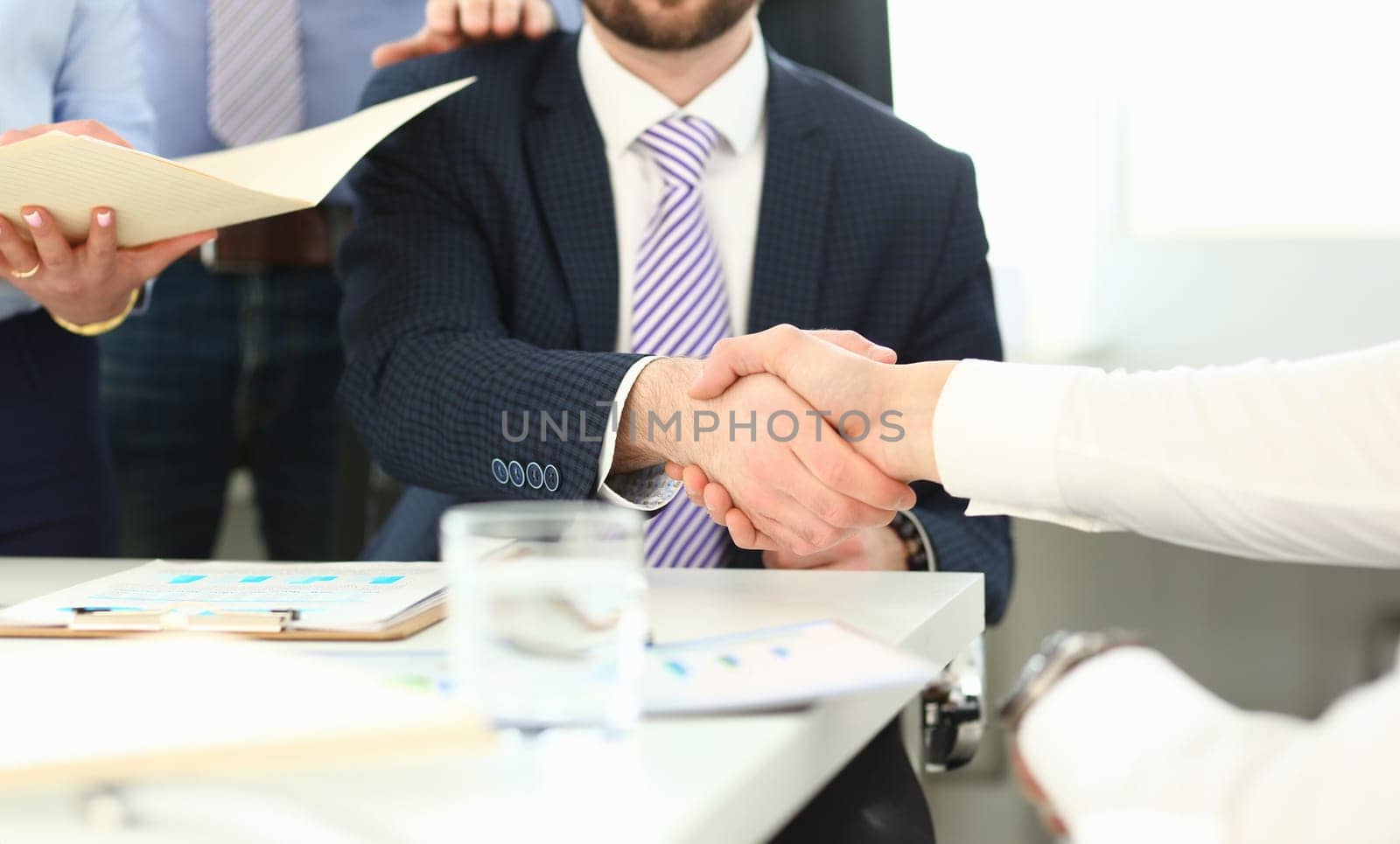 Focus on business male performing friendly gesture towards colleague. Smart man in classy suit shaking hands with young manager. Company meeting concept. Blurred background