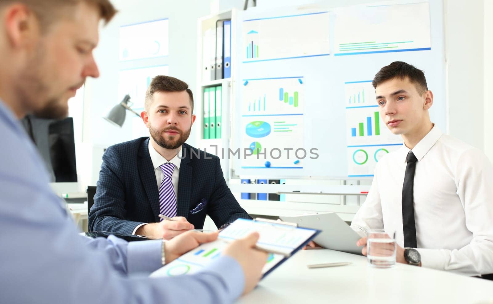 Portrait of young manager talking about with interested boss. Smart colleagues discussing questionable topic. Unexperienced male show businessman work charts. Company meeting concept