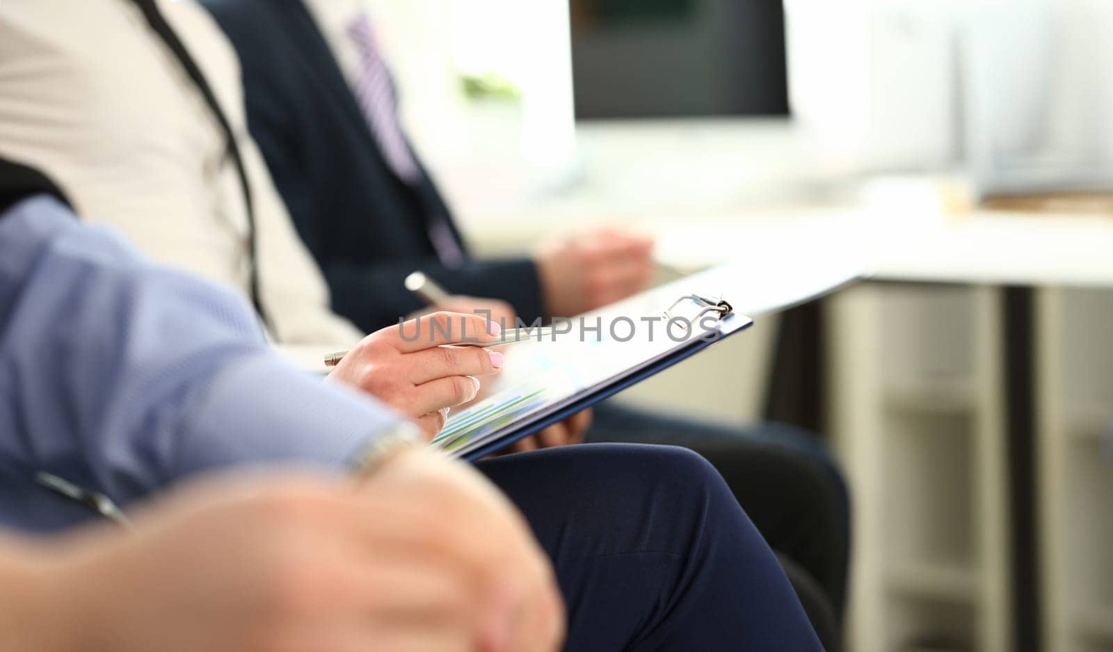 Focus on male hands holding paper folder with important agreements and writing something. Colleagues at biz seminar. Company meeting concept. Blurred background