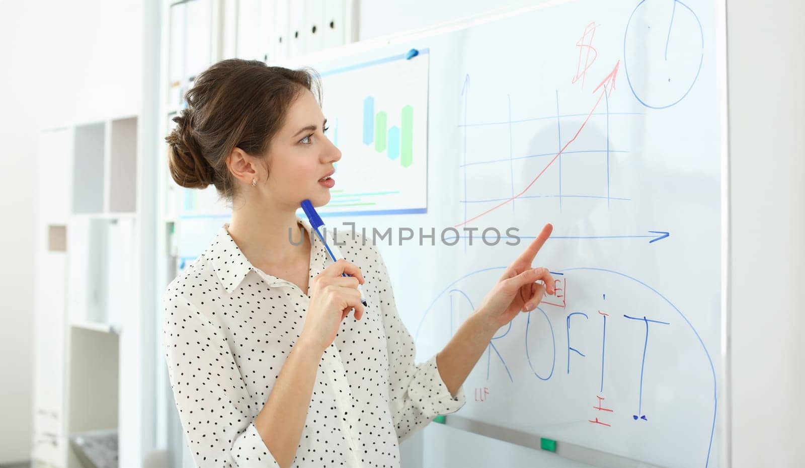 Portrait of attractive manager working in big modern office and discussing important graphs with witty colleagues. Smart woman pointing at complicated charts. Company meeting concept