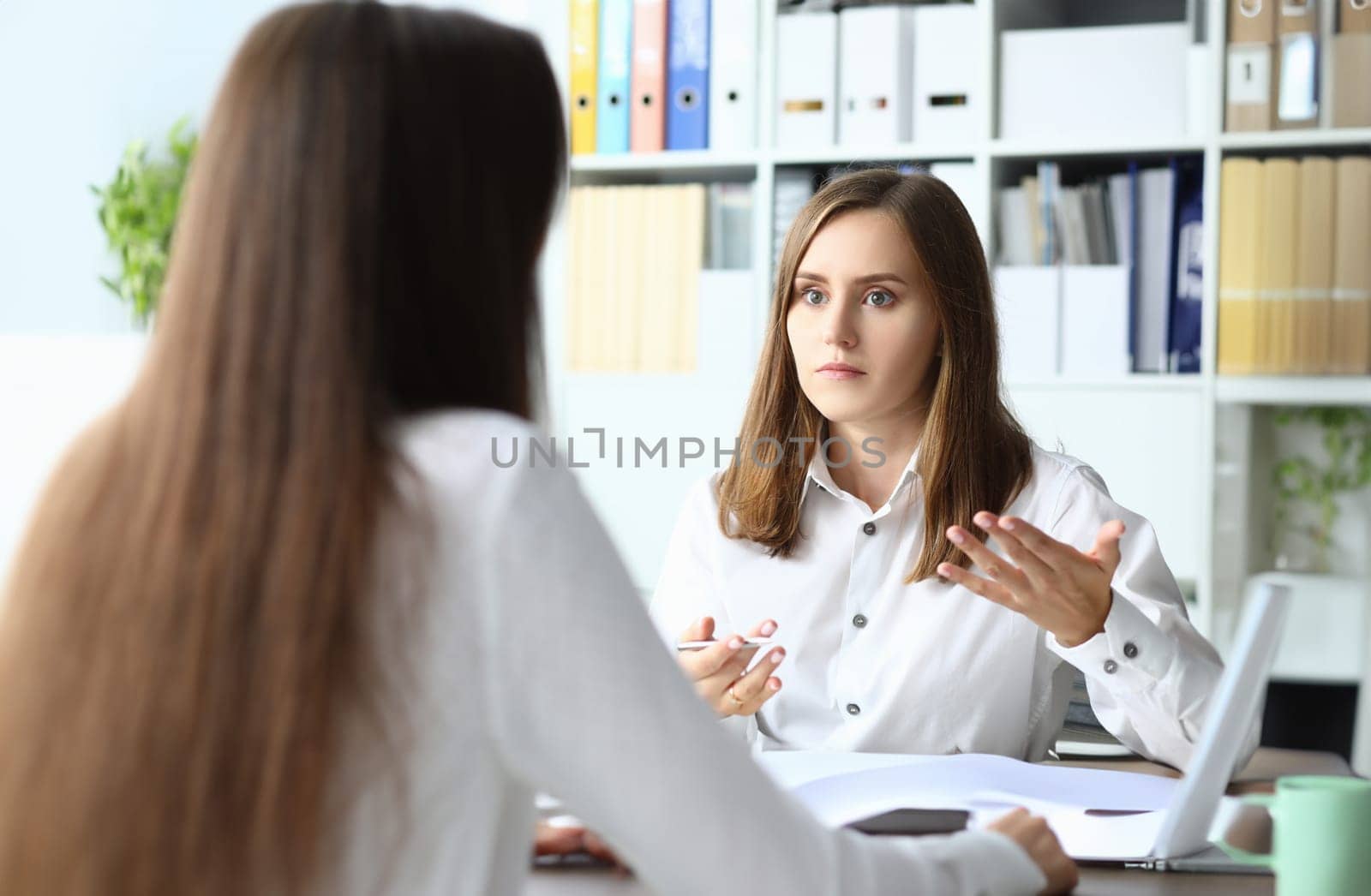 Portrait of smart businesspeople sitting in modern workplace and talking about tactics and profits in paper tablet with significant charts. Accounting office concept