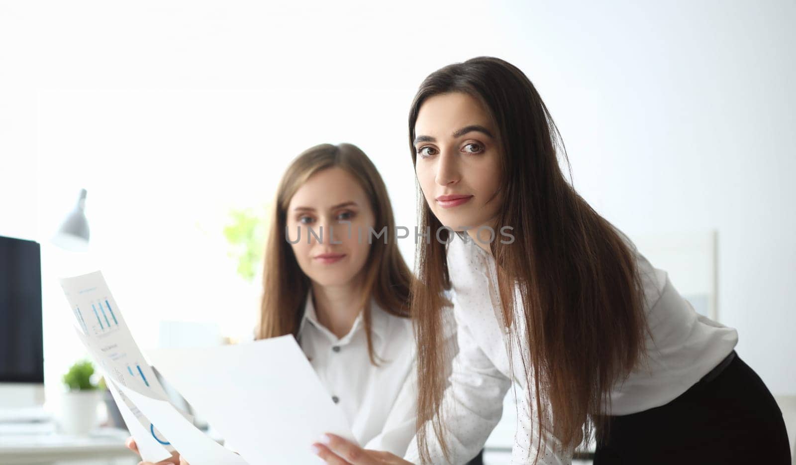 Portrait of joyful businesswoman looking at camera with joy and holding important business document with significant corporation charts and graphs. Accounting office concept
