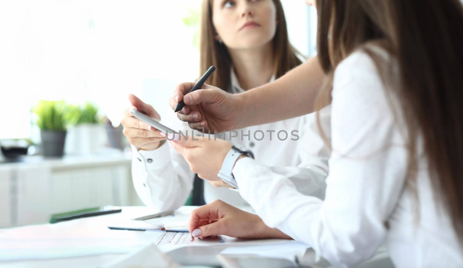 Focus on tender hands of businesspeople holding important corporate documents and pointing at charts and graphs with writing metallic pen. Accounting office concept. Blurred background