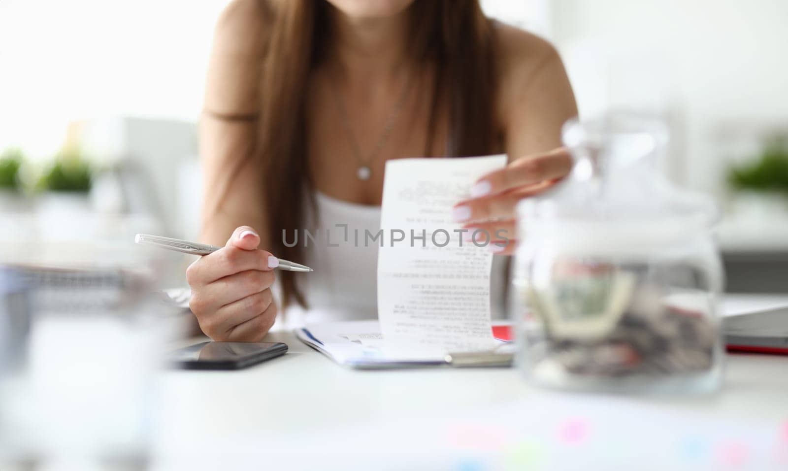 Focus on tender hands of businesswoman sitting indoors with metallic silver pen and important tablet with significant business documents. Office concept. Blurred background