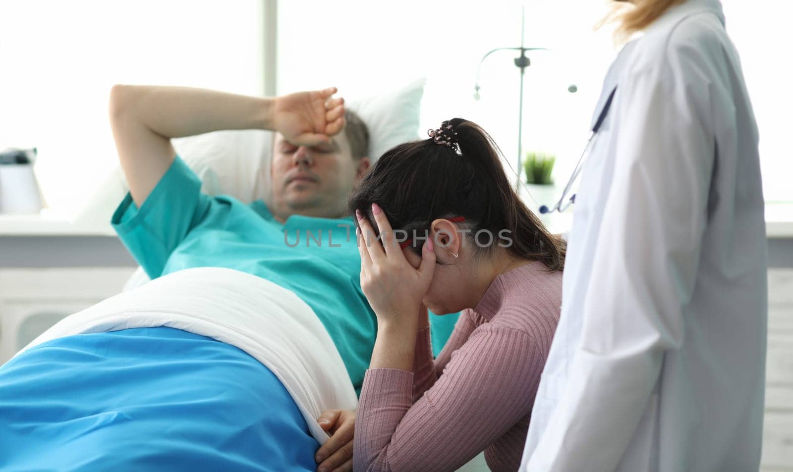 Girl crying near man lying on bed in ward clinic. Monitoring all vital functions patient. Medicine use modern and proven practice diagnostic and treatment methods. Preoperative preparation