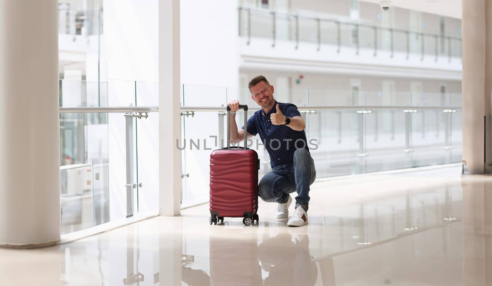 Man with suitcases showing ok gesture in hotel corridor. Quality rest in hotel concept