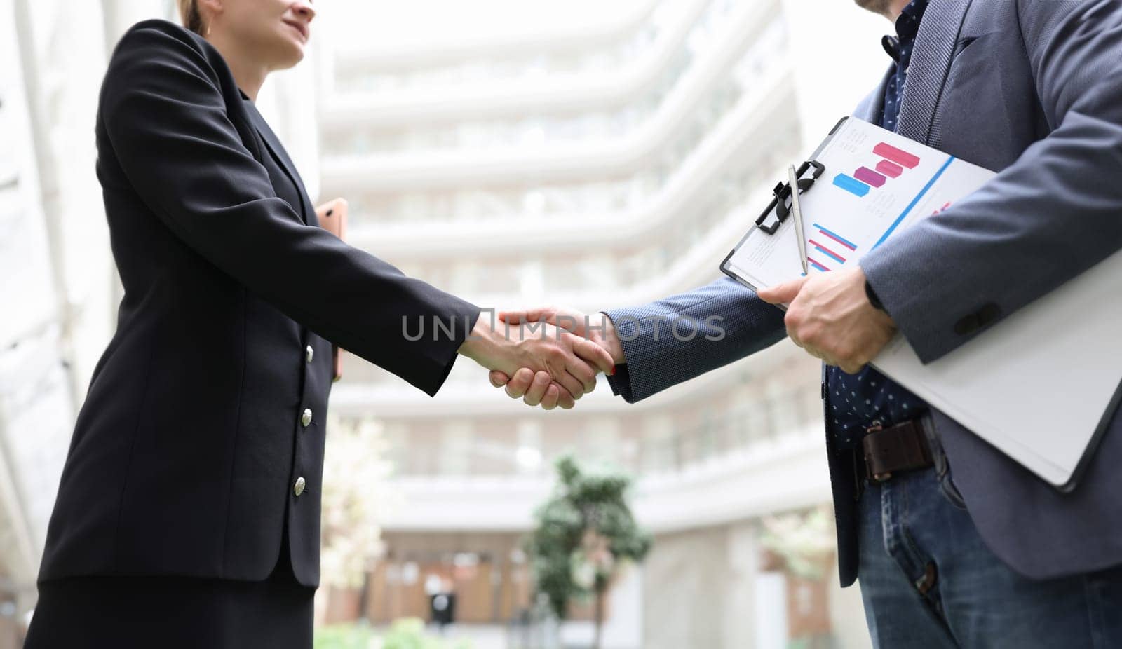Business man and woman with documents shaking hands closeup. Business cooperation concept