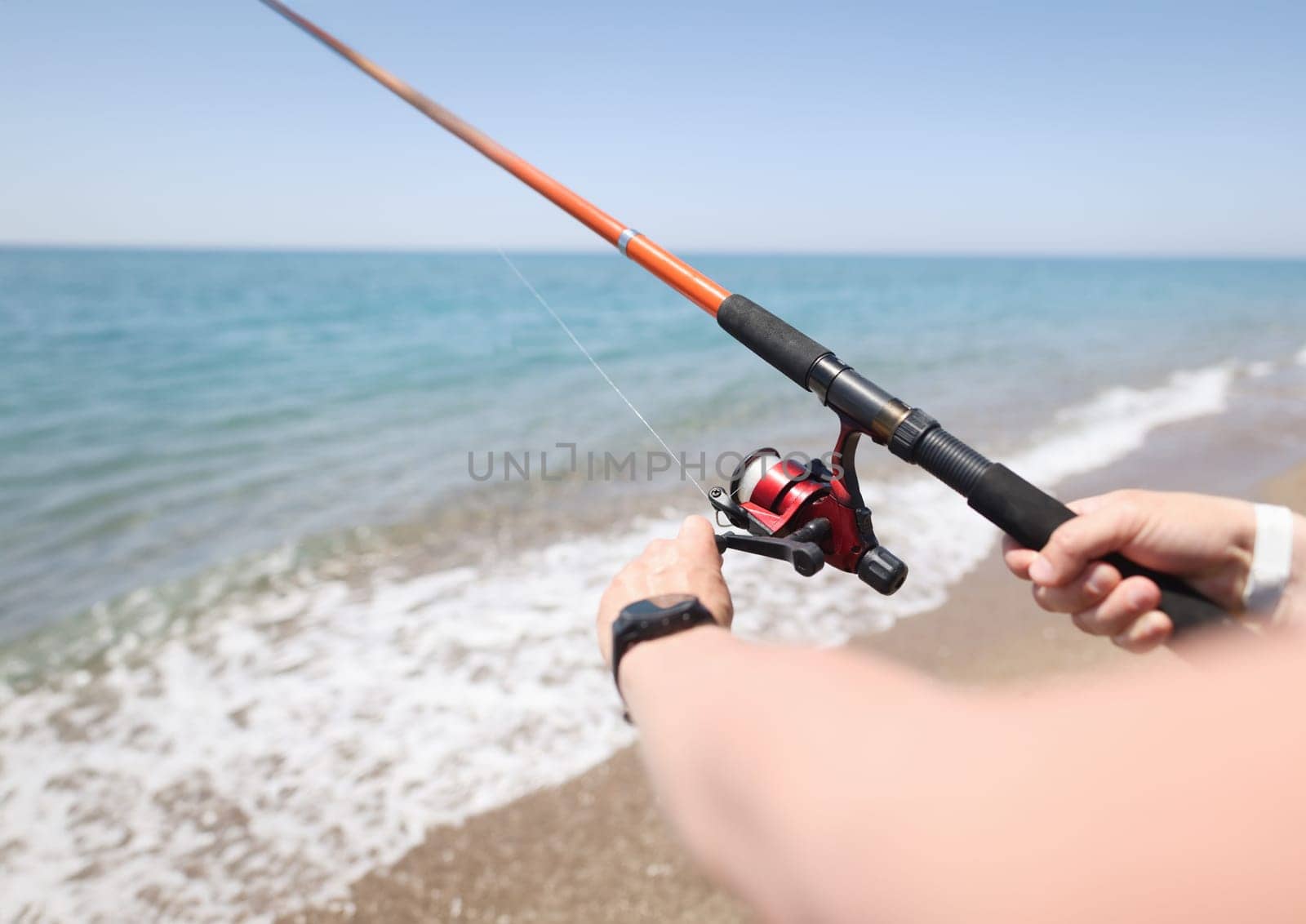 Man fishing with rod on seashore closeup. Men hobby fishing concept