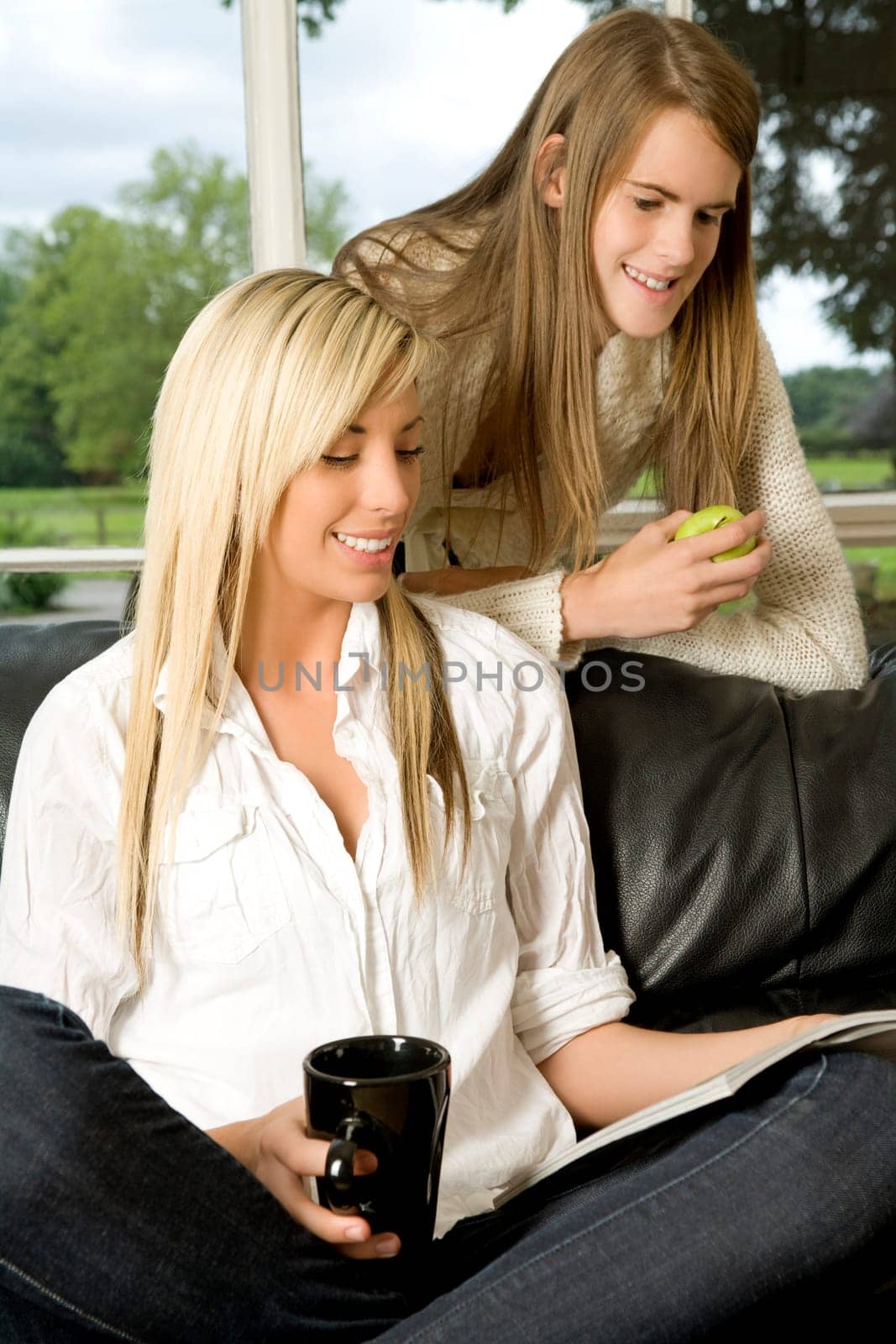 Two friends chatting and relaxing on the sofa at home