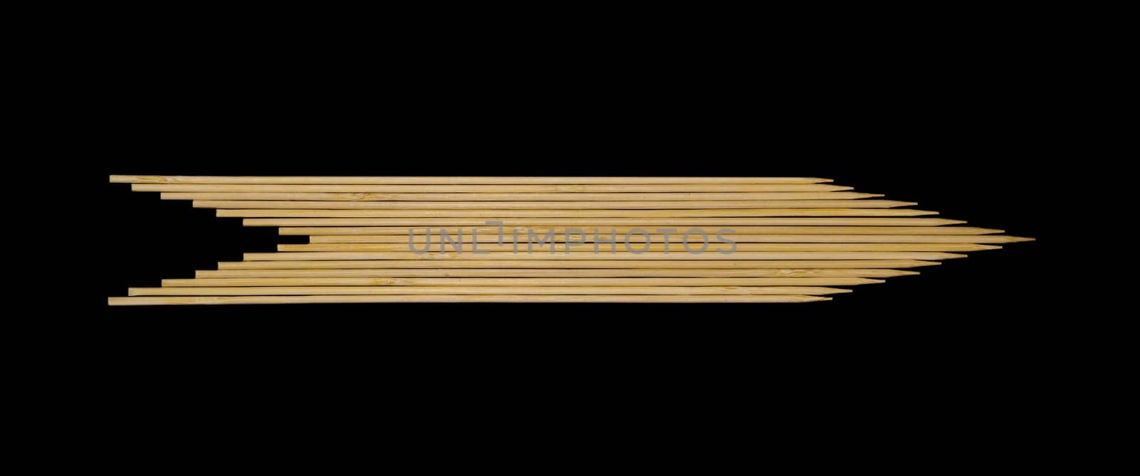 Wooden skewers in the shape of an arrow on a black background.