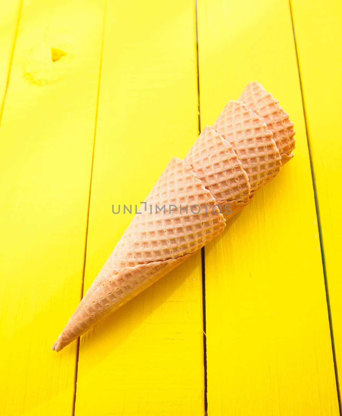 Four ice cream cones on yellow table
