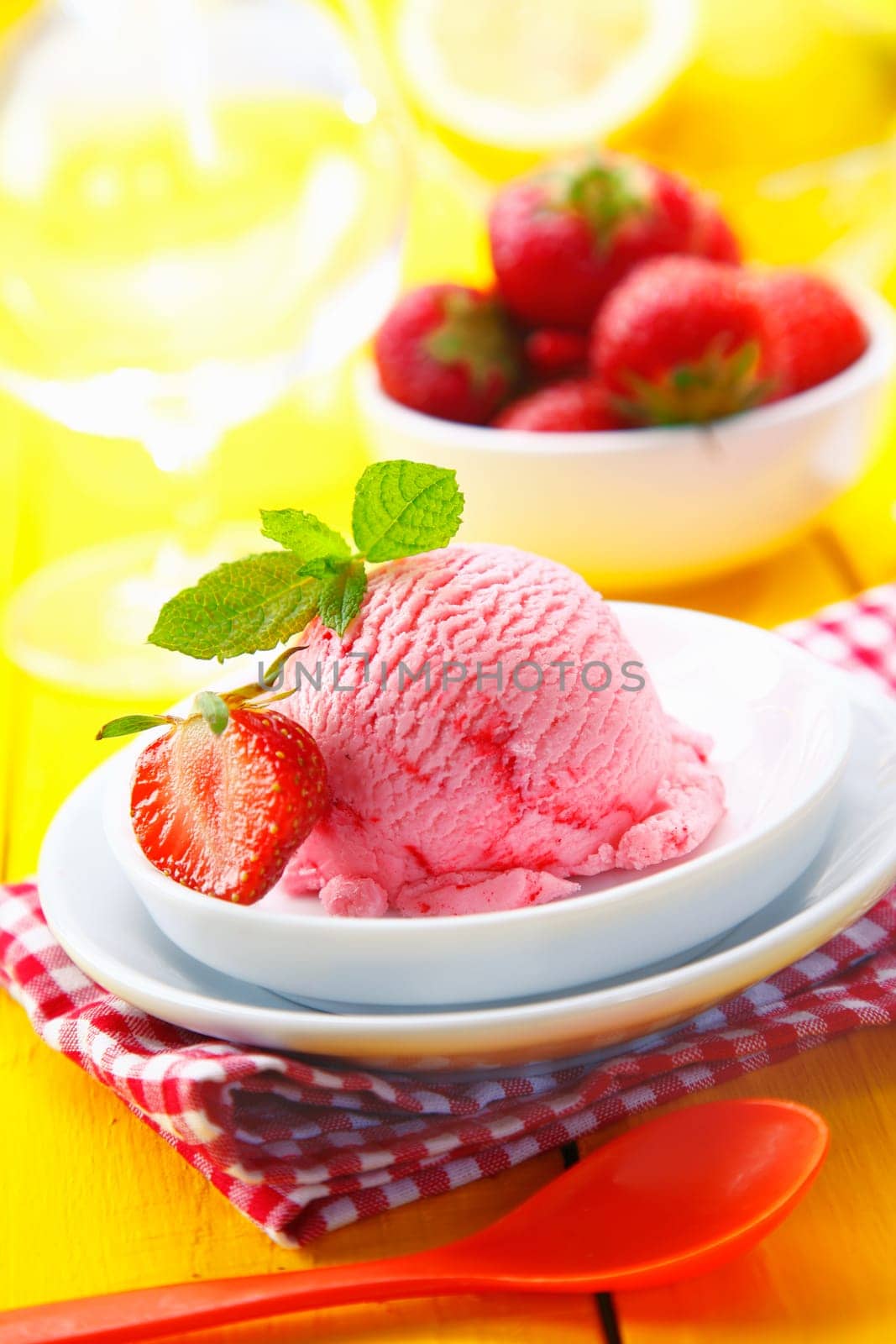 Catering concept with a bowl of creamy strawberry icecream garnished with mint served for dessert on a counrty table setting