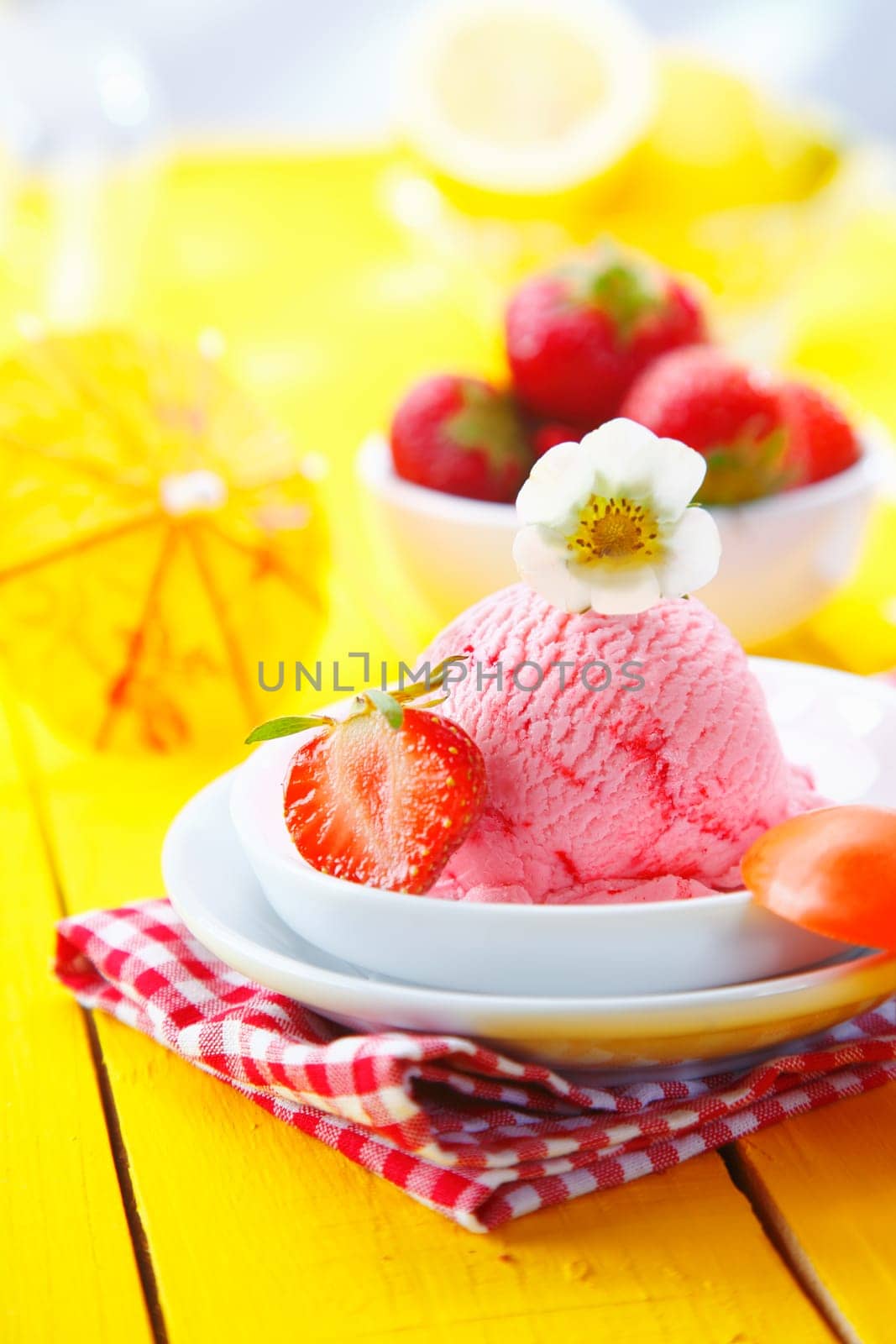 Enjoying a serving of fresh strawberry icecream on a yellow tabletop poolside in summer
