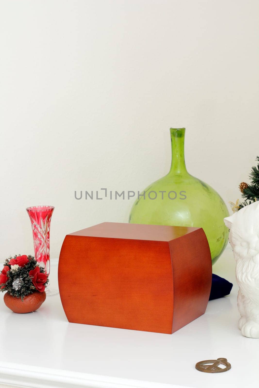 Wood urn filled with loved ones ashes surrounded by memento objects on a white mantle.