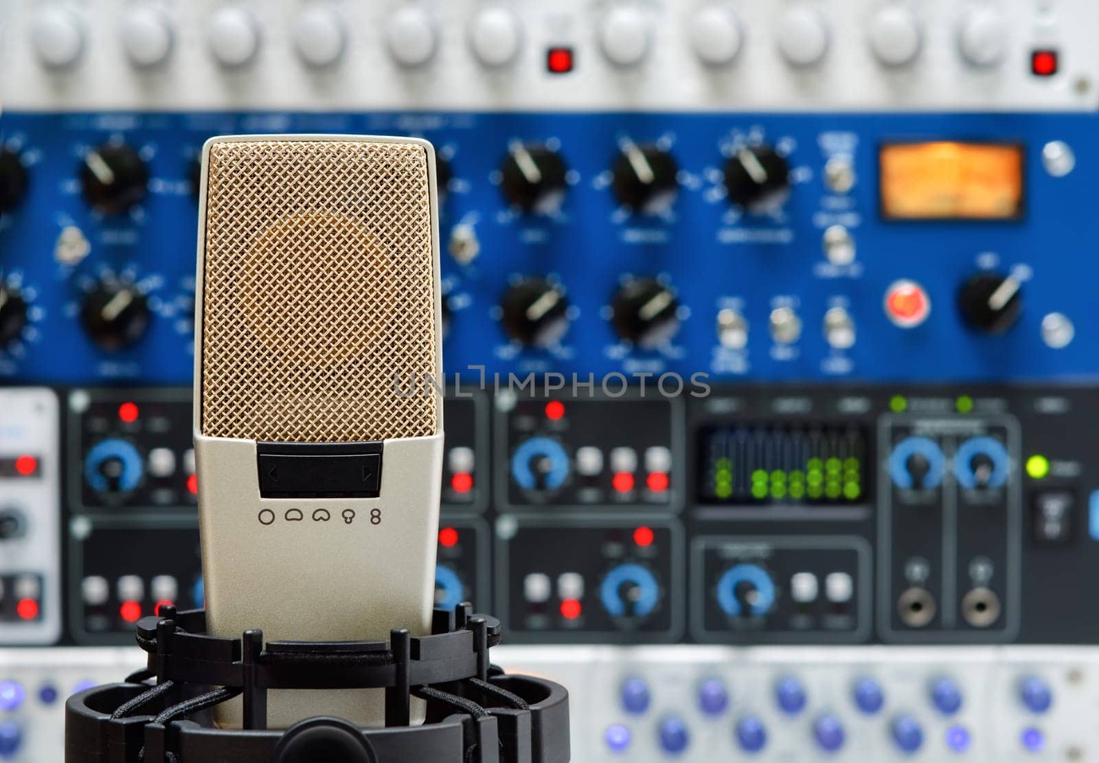 Studio microphone in front of multiple audio devices turned on,blurred background