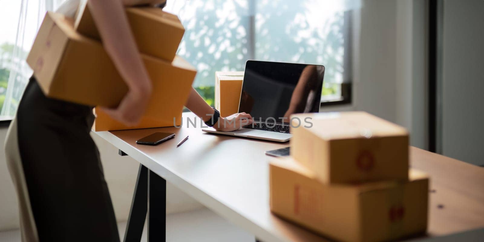 Close up Asian woman using laptop and box to receive and review order online to prepare to pack sell to customers, online small business ideas startup entrepreneur of freelance.