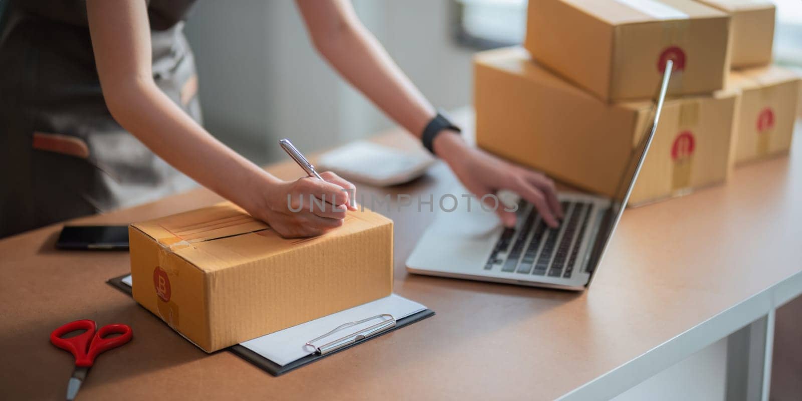 Closeup woman Asian is writing a list of customer on paper before shipping to them, she runs an ecommerce business on websites and social media by nateemee