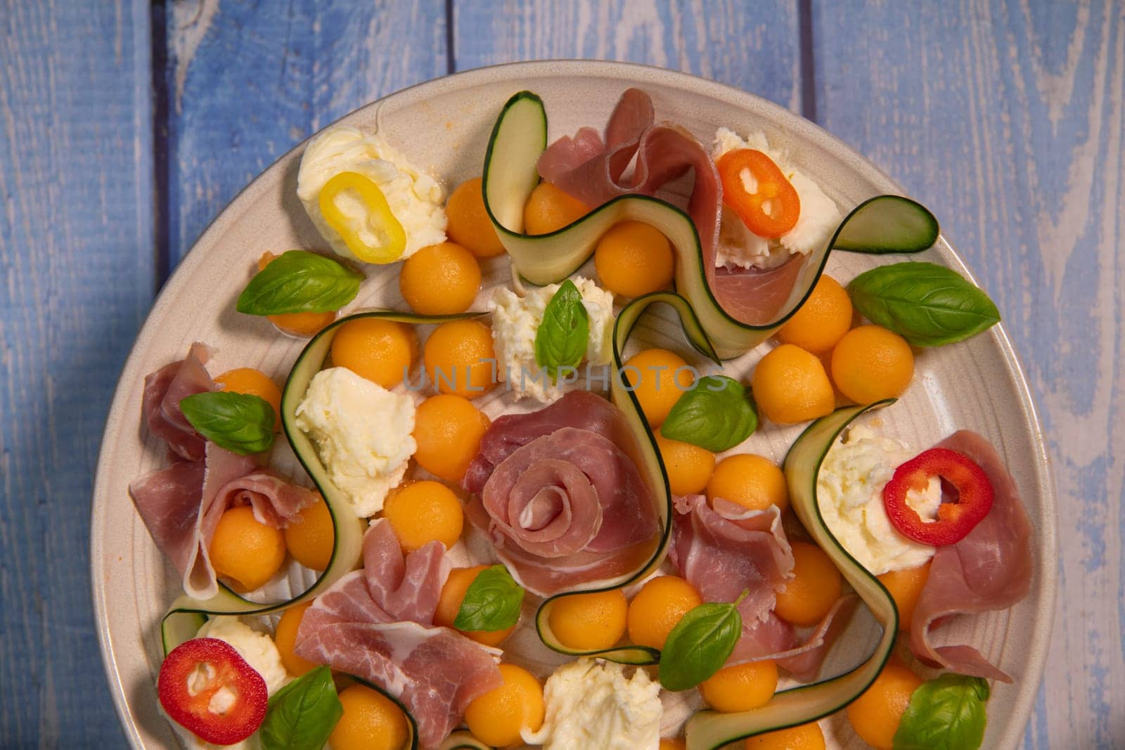 RECIPE FOR MELON, MOZARELLA, BASIL AND CURED HAM SALAD, CUCUMBER SLICE, ORANGE VINAIGRETTE. High quality photo