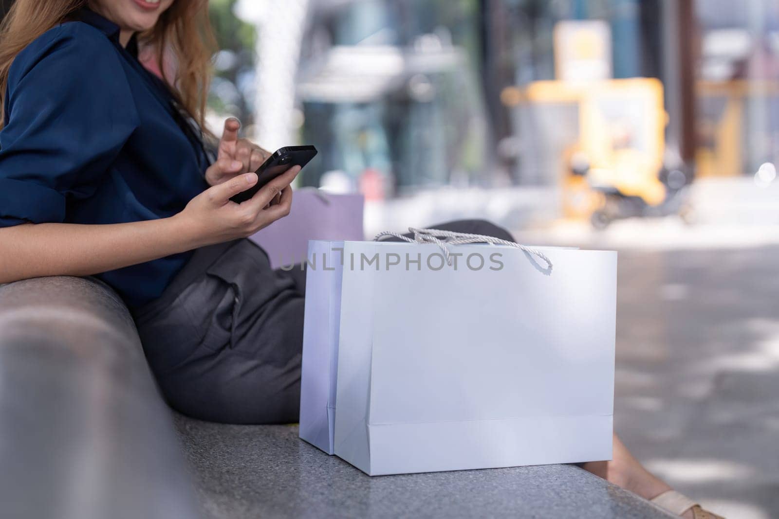 Black Friday, Woman using smartphone and there were shopping bag next to it while sit on the mall by nateemee