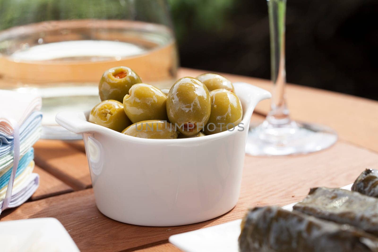 Green olives stuffed with red pimento in small white bowl.
