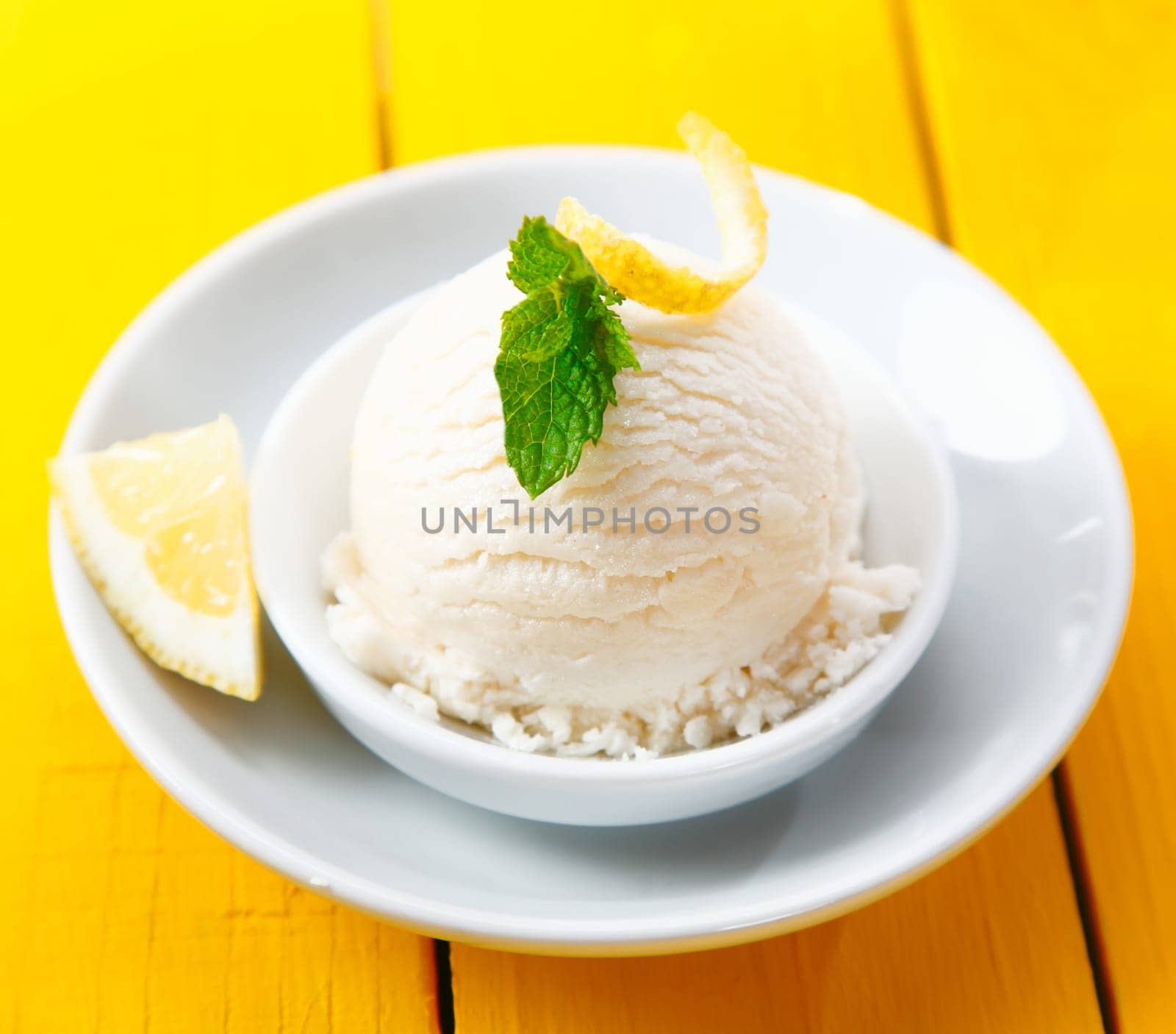 High angle view of a serving of refreshing tangy lemon sorbet served with zest and a slice of lemon