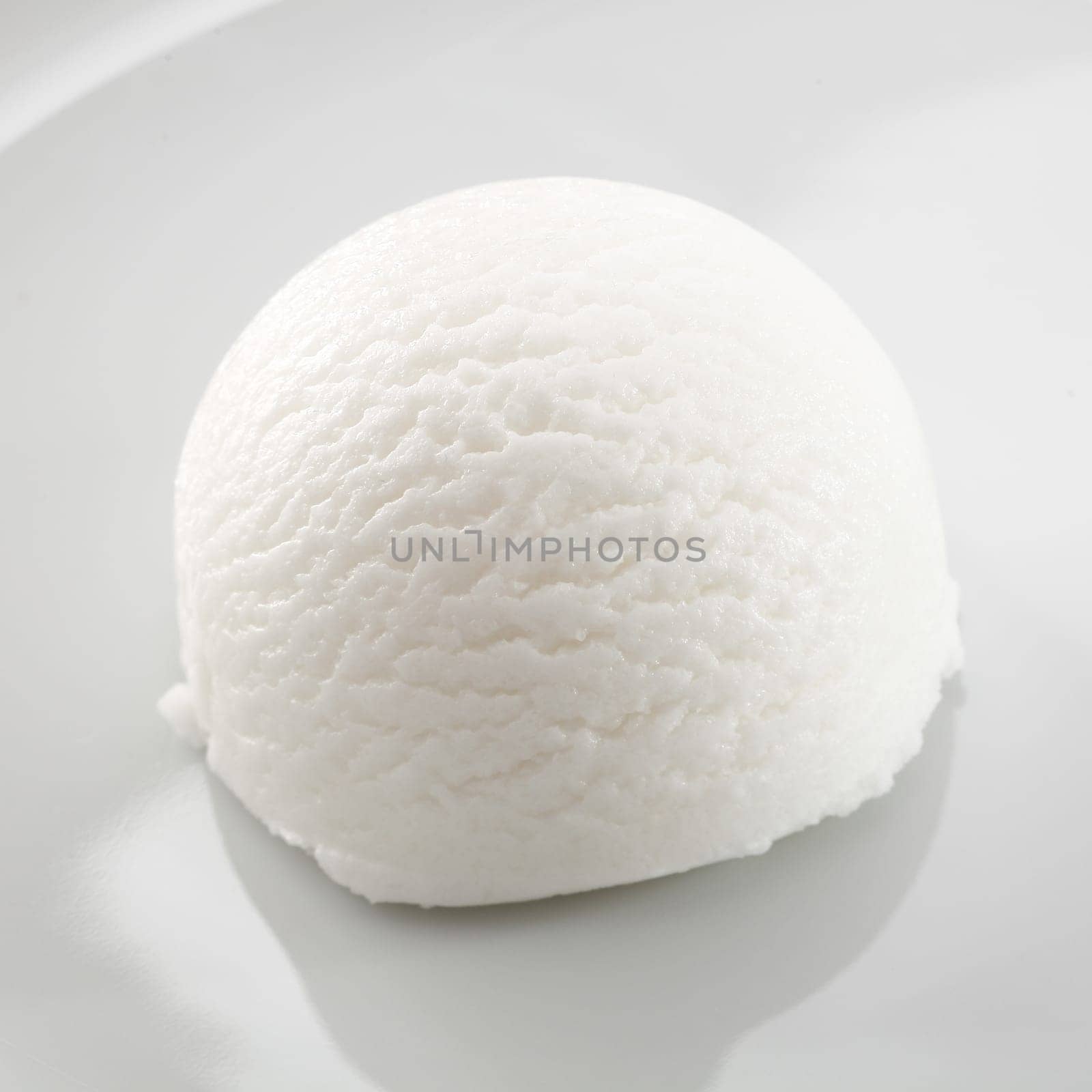 Single scoop of refreshing tangy sour lemon sorbet dessert on a white plate